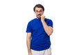 young surprised confident caucasian brunette man with a beard and glasses in a blue t-shirt on a white background