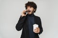 Young surprised indian man with coffee and phone