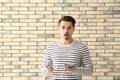 Young surprised man holding piggy bank on brick background. Savings money concept Royalty Free Stock Photo