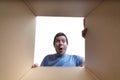 Young surprised man is looking inside cardboard box Royalty Free Stock Photo