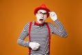 Young surprised mime in red hat and striped t-shirt on blank orange background Royalty Free Stock Photo