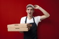 Surprised pizza delivery man gives boxes on a red background, shocked courier delivers an order Royalty Free Stock Photo