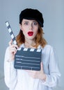 Young surprised redhead woman in hat holding movie clapboard Royalty Free Stock Photo