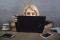 Young surprised and stressed business woman at office desk looking intense to computer screen surrounded by mobile phones in overw