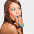 Young surprised woman holding a turquoise bracelet with bright m