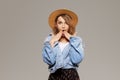 Young surprised woman model in a fashionable hat and denim jacket on a gray background.