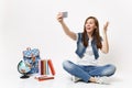 Young surprised woman student doing taking selfie shot on mobile phone and spreading hands near globe, backpack, school Royalty Free Stock Photo