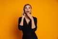 Young surprised woman talking on mobile phone isolated over orange background Royalty Free Stock Photo