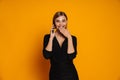 Young surprised woman talking on mobile phone while standing isolated over orange background Royalty Free Stock Photo