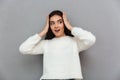 Young surprised woman in white soft sweater holding her head, lo Royalty Free Stock Photo