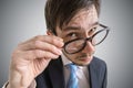 Young suspicious businessman is looking at you through glasses