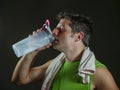 Young sweaty attractive and fit sport man drinking water holding bottle cooling off after hard fitness workout at gym club Royalty Free Stock Photo