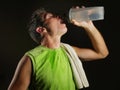 Young sweaty attractive and fit sport man drinking water holding bottle cooling off after hard fitness workout at gym club Royalty Free Stock Photo