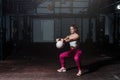 Young sweaty fit muscular strong girl doing hardcore cross workout training for shoulder muscles with heavy kettlebell in the gym Royalty Free Stock Photo