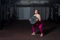 Young sweaty muscular strong fit girl holding big heavy barbell weight plate with her hands and lifting it up as hardcore cross wo Royalty Free Stock Photo