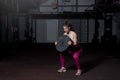 Young sweaty muscular strong fit girl holding big heavy barbell weight plate with her hands and lifting it up as hardcore cross wo Royalty Free Stock Photo