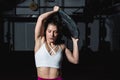 Young sweaty muscular strong fit girl holding big heavy barbell weight plate with her hands and lifting it up as hardcore cross wo Royalty Free Stock Photo