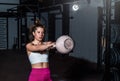 Young sweaty strong muscular fit girl holding heavy kettlebell with her hands and doing swing hardcore cross workout training in t