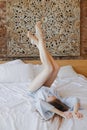 Young sweet girl is lying on bed with her legs raised Royalty Free Stock Photo