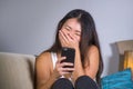 Young sweet happy and pretty Asian Korean girl using internet social media app on mobile phone laughing cheerful having fun at hom Royalty Free Stock Photo