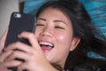 Young sweet happy and pretty Asian Korean girl using internet social media app on mobile phone smiling cheerful lying on home sofa Royalty Free Stock Photo