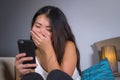 Young sweet happy and pretty Asian Korean woman using internet social media app on mobile phone laughing cheerful having fun at ho Royalty Free Stock Photo