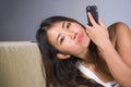 Young sweet happy and pretty Asian Korean woman using internet social media app on mobile phone posing relaxed at home sofa couch Royalty Free Stock Photo