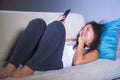 Young sweet happy and pretty Asian Korean woman using internet social media app on mobile phone smiling relaxed lying at home sofa Royalty Free Stock Photo
