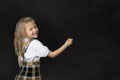 Young sweet junior schoolgirl with blonde hair smiling happy writing with chalk in blackboard