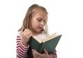 Young sweet little 6 or 7 years old with blond hair girl reading a book looking curious and fascinated Royalty Free Stock Photo