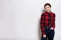 A young sylish hipster girl wearing red checked shirt and jeans holding her hand in the pocket having happy expression standing ne Royalty Free Stock Photo