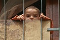 Young Syrian boy looks through the fence of his house in Homs