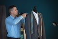 Young tailor taking measurements of jacket on mannequin in atelier Royalty Free Stock Photo