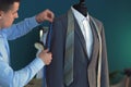 Young tailor taking measurements of jacket on mannequin in atelier Royalty Free Stock Photo