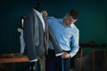 Young tailor taking measurements of jacket on mannequin in atelier Royalty Free Stock Photo