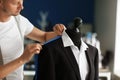 Young tailor taking measurements of male jacket on mannequin in atelier Royalty Free Stock Photo