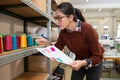 Young tailor woman looking at color spool thread