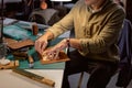 young talented craftsman marks holes in the leather