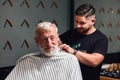 Young talented experienced barber enjoying his work at barbershop