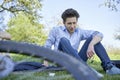 Young talking man sitting in a lawn during a bike tour in beautiful greenery