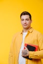 Young tall handsome man in a yellow shirt holding notebooks over yellow