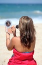 Young tanned woman putting make up on whilst on the beach