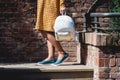 Young tanned woman standing on the stone stairs. Woman in a yellow dress and blue shoes with white backpack in hands. Royalty Free Stock Photo