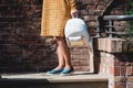 Young tanned woman standing on the stone stairs. Woman in a yellow dress and blue shoes with white backpack in hands. Royalty Free Stock Photo