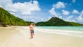 young tanning men in swim short at a white tropical beach Anse Volbert beach Praslin Seychelles