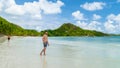 young tanning men in swim short at a white tropical beach Anse Volbert beach Praslin Seychelles