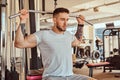 Young tattoed man is doing exercise for back on training apparatus in gym Royalty Free Stock Photo