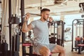 Young tattoed man is doing exercise for back on training apparatus in gym Royalty Free Stock Photo