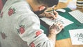 Young tattoo artist drawing sketch inside ink studio - Hipster tattoer at work - Contemporary skin trends generation - - Focus on