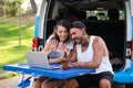 Young tattooed couple greet and talk in a laptop video call during a van trip. Royalty Free Stock Photo